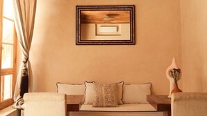 A cozy room with a wooden ceiling, a sofa with cushions, two armchairs, and a framed picture on the wall. - Large suite ideal for families (Marrakesh)