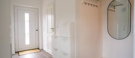 A hallway with a white door, a white cabinet with drawers, a towel rack, and a mirror on the wall.