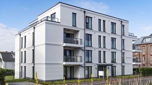 A modern multi-story residential building with balconies, large windows, and a flat roof. - Seeblick Nordlicht - Comfortable accommodation on Wangerooge with terrace and garden (Wangerooge)