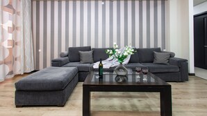 A modern living room with a grey sectional sofa, a glass coffee table, and a decorative vase with flowers.