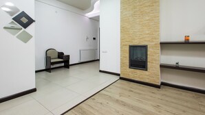 A modern interior with a wooden floor, a fireplace, and a seating area with a chair.