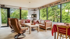 A spacious living room with a large window, a sofa, a coffee table, and a dining area with a table and chairs.