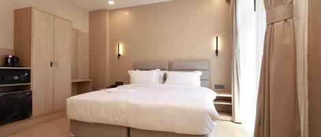 A modern hotel room with a large bed, a wardrobe, a desk, and a bathroom.