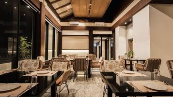 A restaurant with multiple tables and chairs, a wooden ceiling, and large windows.