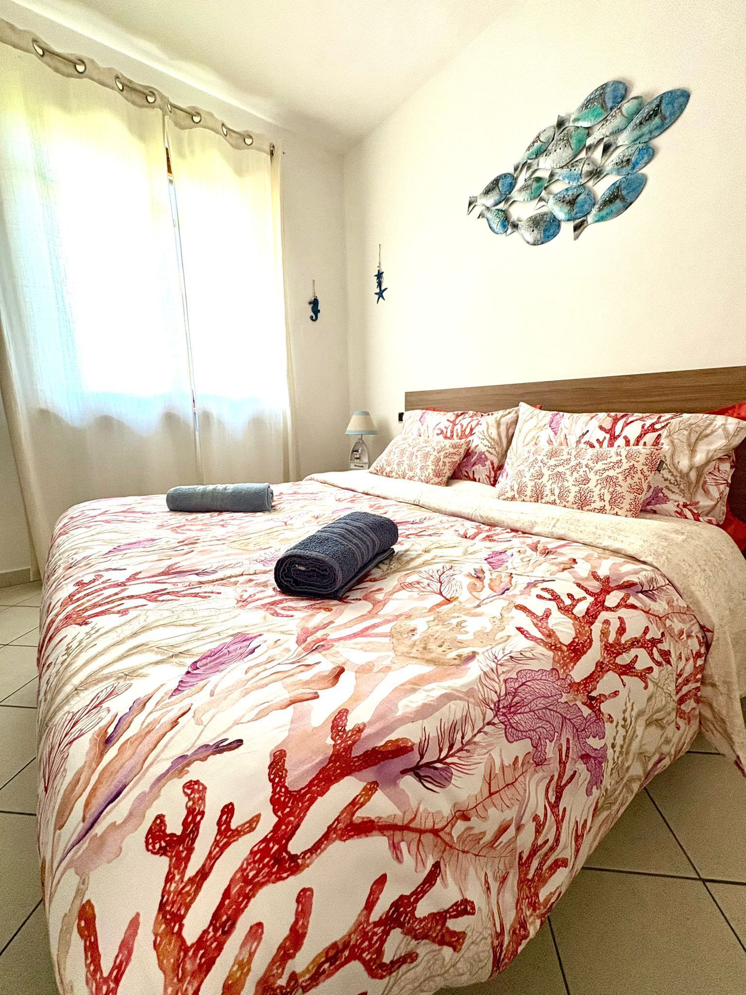 Een bed met een bloemenprint deken, een hoofdbord en een wanddecoratie.