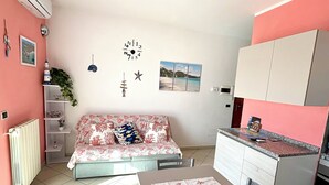 Un espace de vie compact comprenant une kitchenette, un coin repas et un canapé.