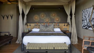 Une chambre à coucher avec un lit à baldaquin, un banc, une chaise et un mur orné de motifs décoratifs en forme de soleil.