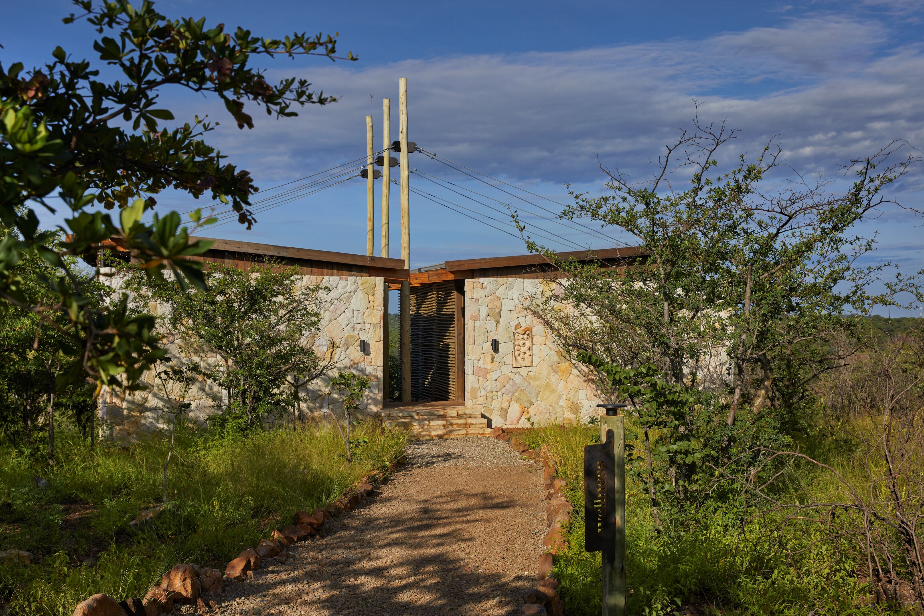Un bâtiment en pierre avec un toit en bois et un chemin de gravier menant à une porte en bois.