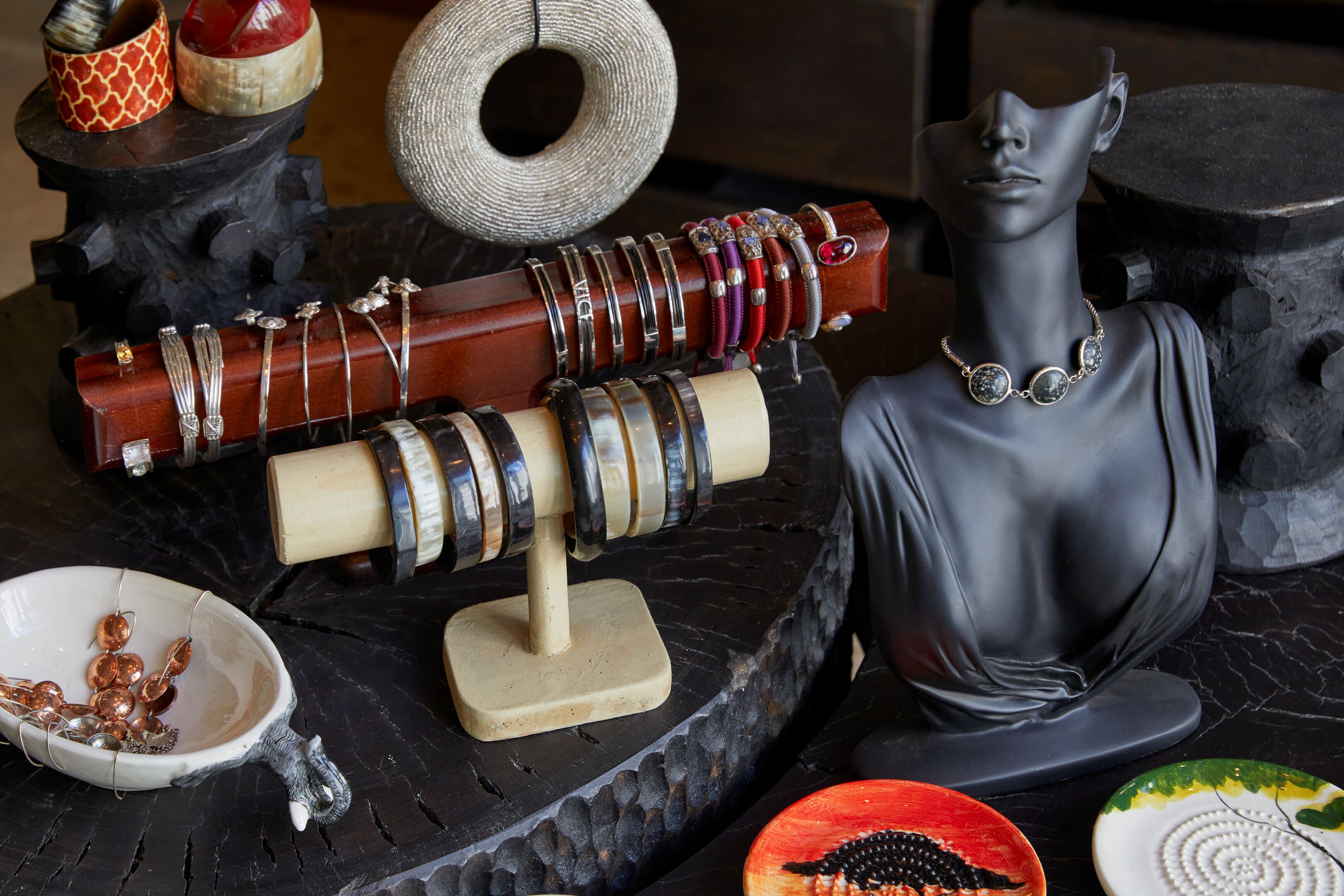 A display of jewelry on a stand with a bust sculpture.