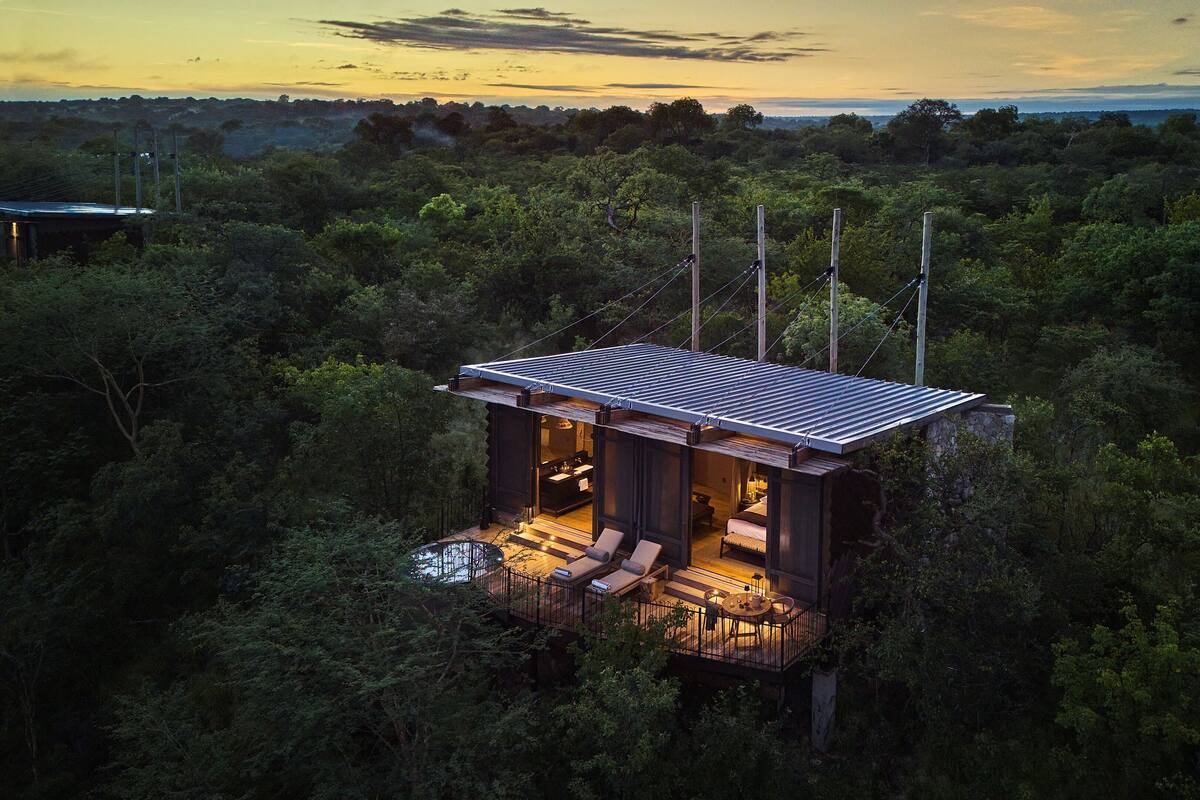 A secluded cabin with a deck, surrounded by dense forest.