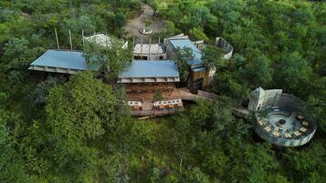 An aerial view of a resort with multiple buildings, outdoor seating areas, and a circular structure.
