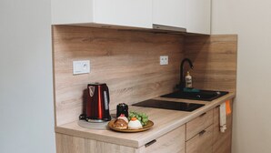 A modern kitchen with a wooden countertop, a sink, a kettle, and a bottle of dish soap. - FatCat Apartments (Kraków)