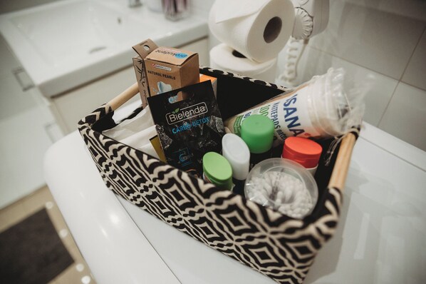 A bathroom with a white sink, a toilet, and a patterned basket containing toiletries. - FatCat Apartments (Kraków)