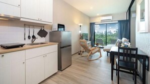 Een moderne keuken met witte kastjes, een roestvrijstalen koelkast en een eethoek met een houten tafel en stoelen.