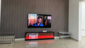 Uma sala de estar moderna com uma TV de tela plana fixada na parede, uma mesa de centro de vidro e uma cesta de vime.
