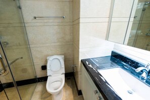 A bathroom with a toilet, a glass shower enclosure, and a sink with a marble countertop. - Travel Hub Near Business Bay By Al Taj (Dubai)