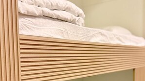 Uma cama beliche com estrutura de madeira e roupa de cama branca.