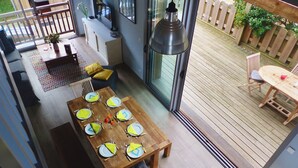 A dining area with a wooden table set for six, a sofa, and a TV in the background.