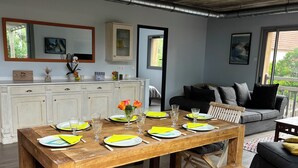 A dining area with a wooden table set for four, a sofa, and a cabinet with a mirror above it.