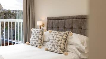 A bed with a tufted headboard, two patterned pillows, and a bedside lamp.