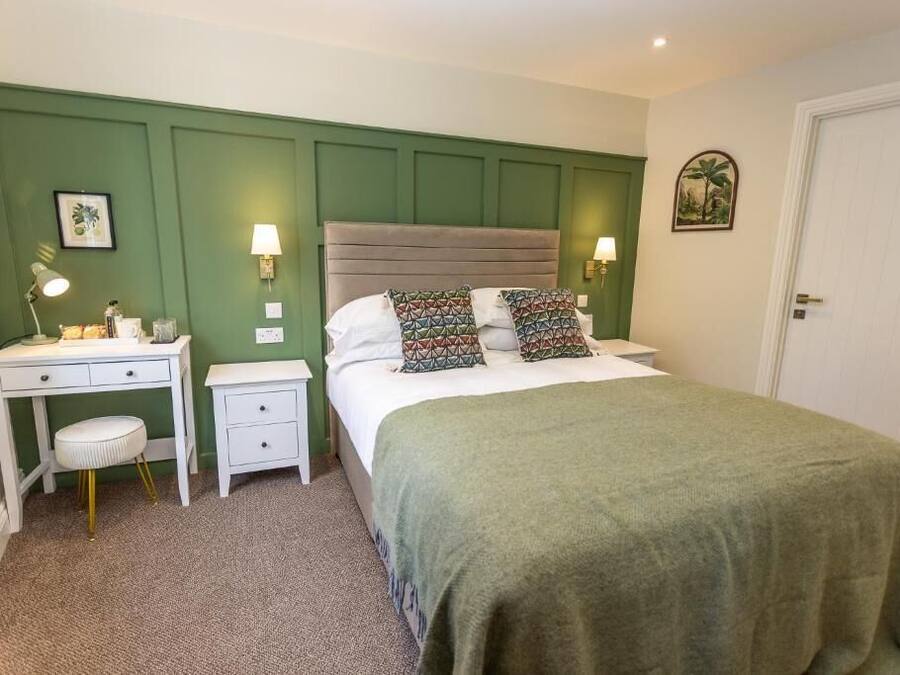 Un dormitorio con cama, mesitas de noche, escritorio y silla.
