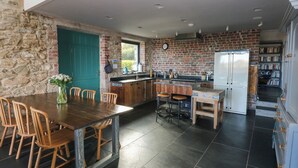 Een keuken met een stenen muur, een blauwgroene deur en een witte koelkast.
