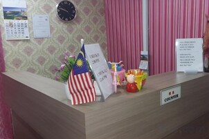 Una recepción con un reloj, una bandera y un letrero que indica la zona de atención al cliente.