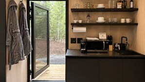 Eine moderne Küche mit integrierter Klimaanlage, einer Kaffeemaschine und einer Mikrowelle. Über der Arbeitsfläche befinden sich Holzregale mit verschiedenen Küchenutensilien.