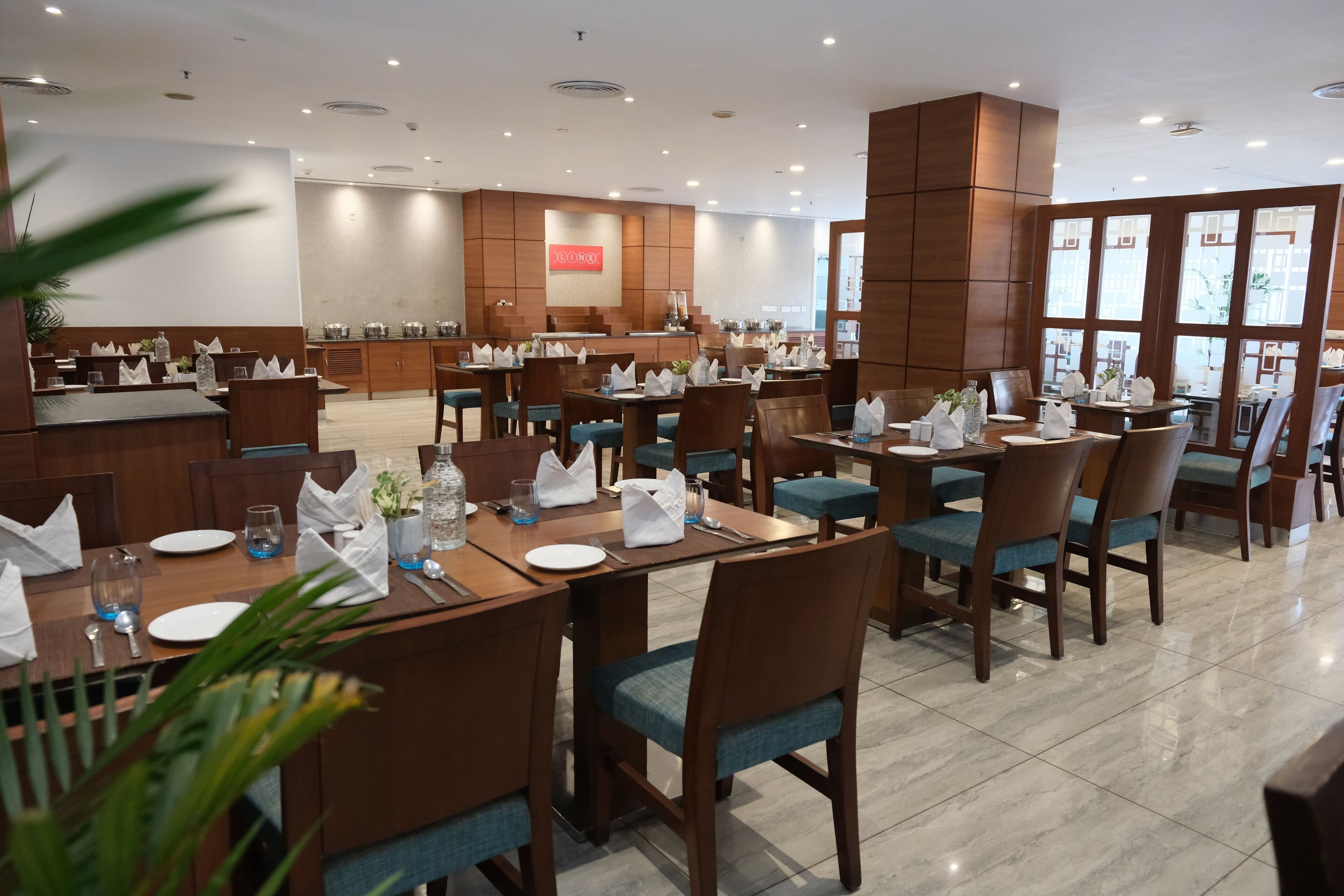 Een restaurant met houten tafels en stoelen, een keukenhoek, en een bord aan de muur.