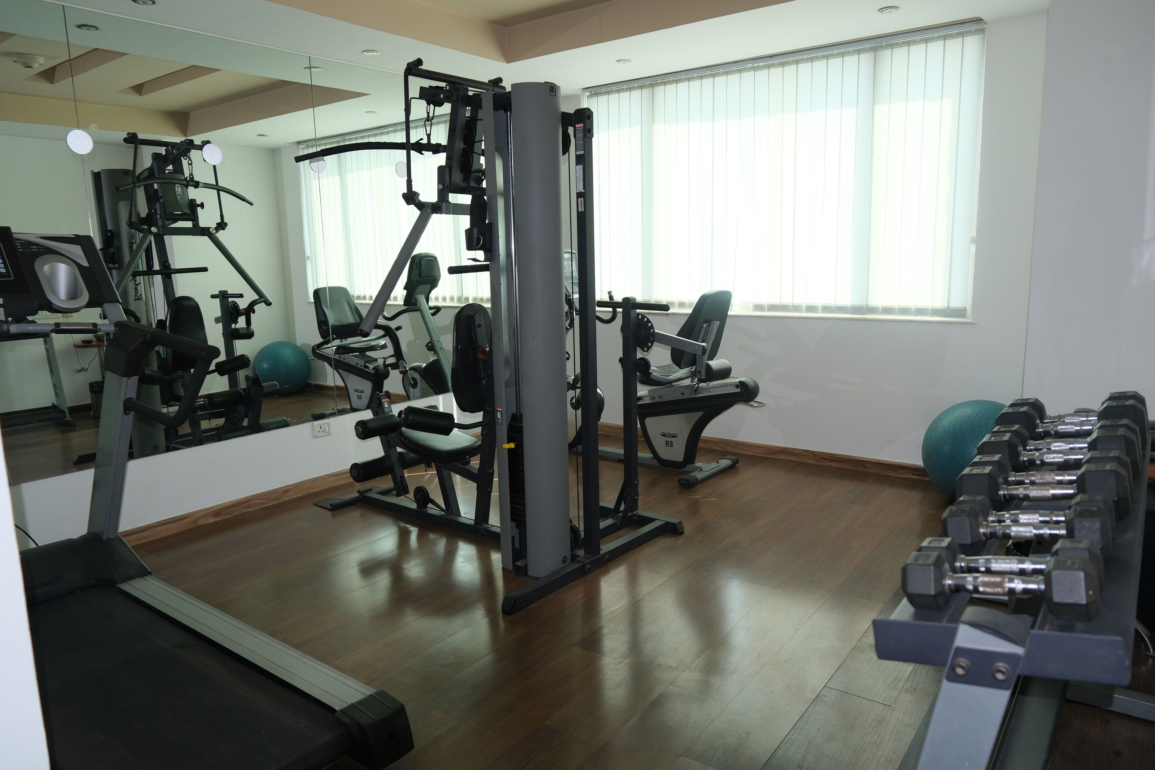 Een sportschool met trainingsapparatuur, loopband en spiegel.