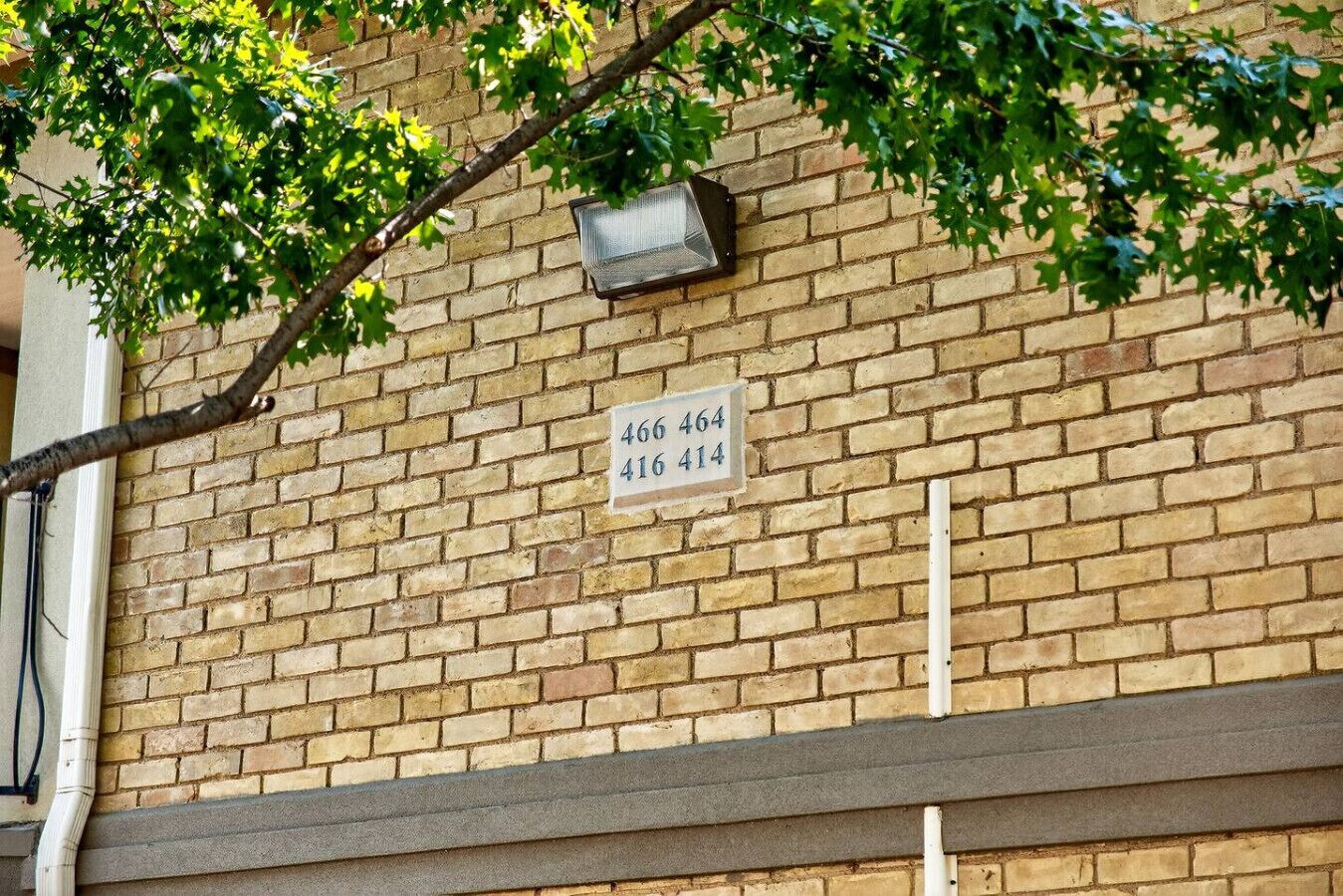 Un muro de ladrillo con un cartel que muestra los números de apartamentos 466, 464, 416 y 414.