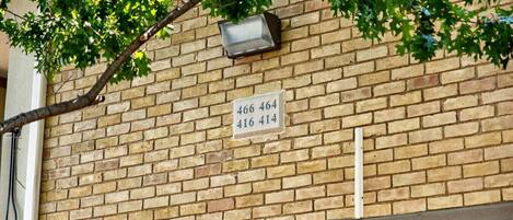 Un muro de ladrillo con un cartel que muestra los números de apartamentos 466, 464, 416 y 414.