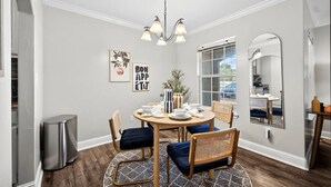 A dining area with a round table, chairs, a chandelier, and a mirror on the wall. - Walk to AT&T Stadium | Modern 2BR With Backyard (Arlington)