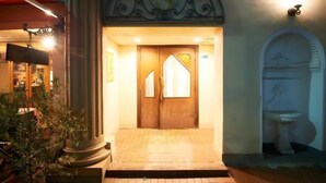 A hotel entrance with a wooden double door, a tiled entrance area, and a decorative archway above the door. - S’CASA Nishishinjuku (Tokyo)