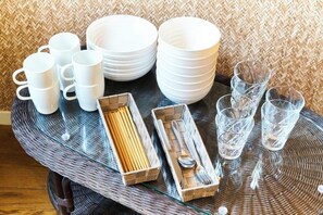 A dining table with stacked white plates, cups, and glasses, along with a box of utensils. - S’CASA Nishishinjuku (Tokyo)