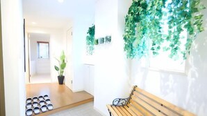 A hallway with a wooden bench, a potted plant, and a wall-mounted plant. - S’CASA Nishishinjuku (Tokyo)