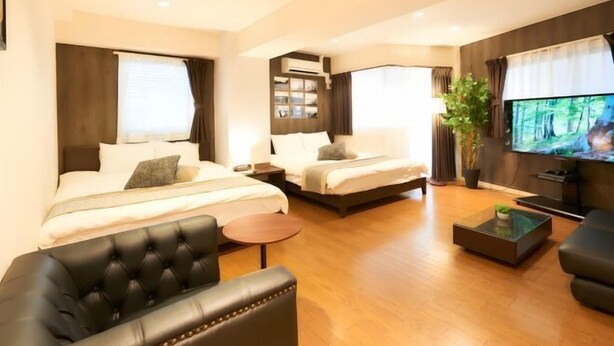 A hotel room with a bed, a sofa, a TV, and a small table. - S’CASA Nishishinjuku (Tokyo)