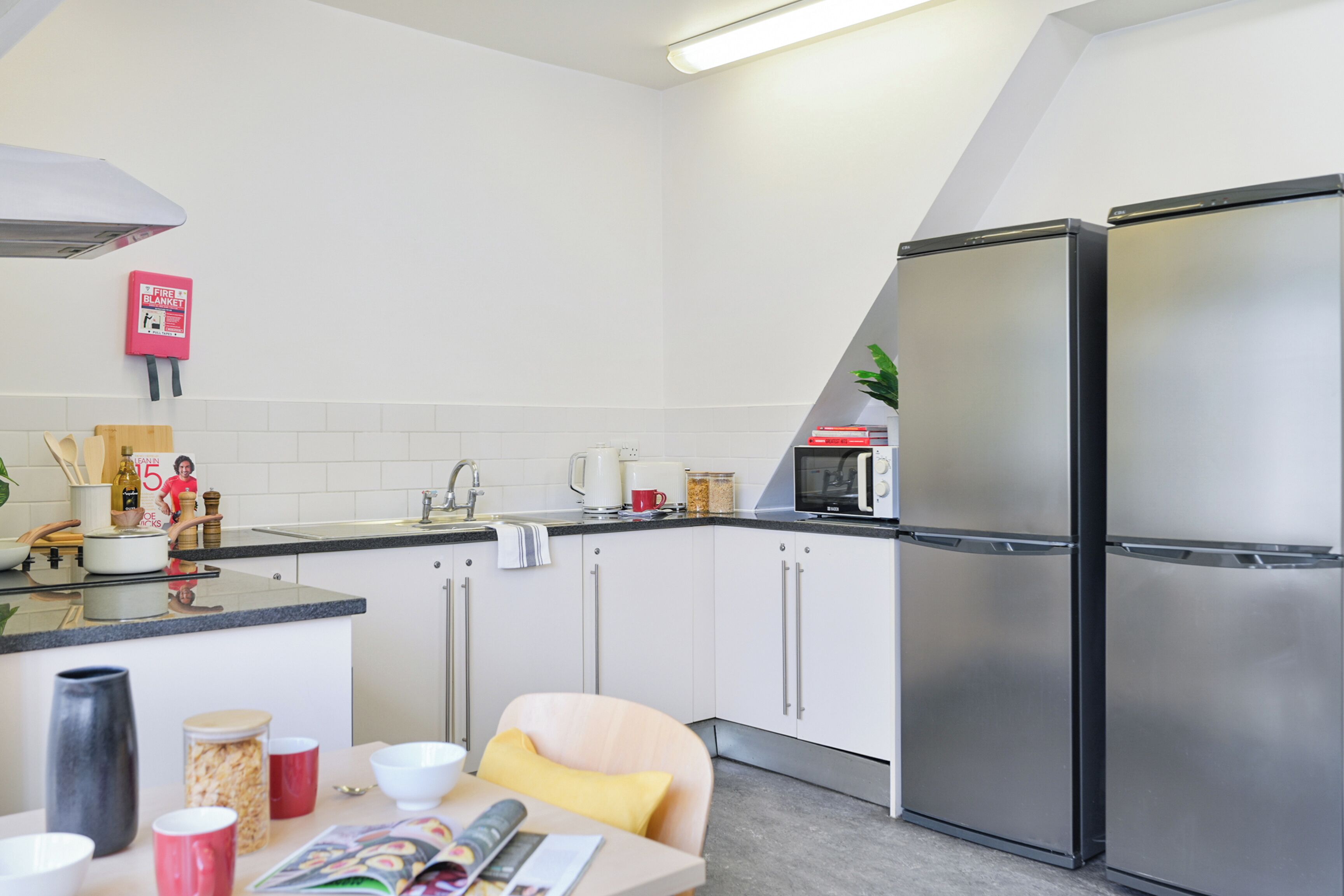 A modern kitchen with stainless steel appliances, a white tiled backsplash, and a small dining area with a table and chairs.