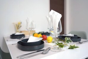 Une table à manger dressée avec un bol noir, un verre à vin, une fourchette et une cuillère.