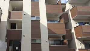 A multi-story residential building with balconies, a door, and a window. - WANO (Osaka)