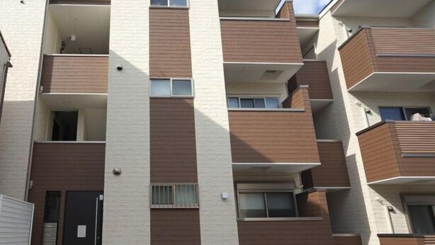A multi-story residential building with balconies, a door, and a window. - WANO (Osaka)
