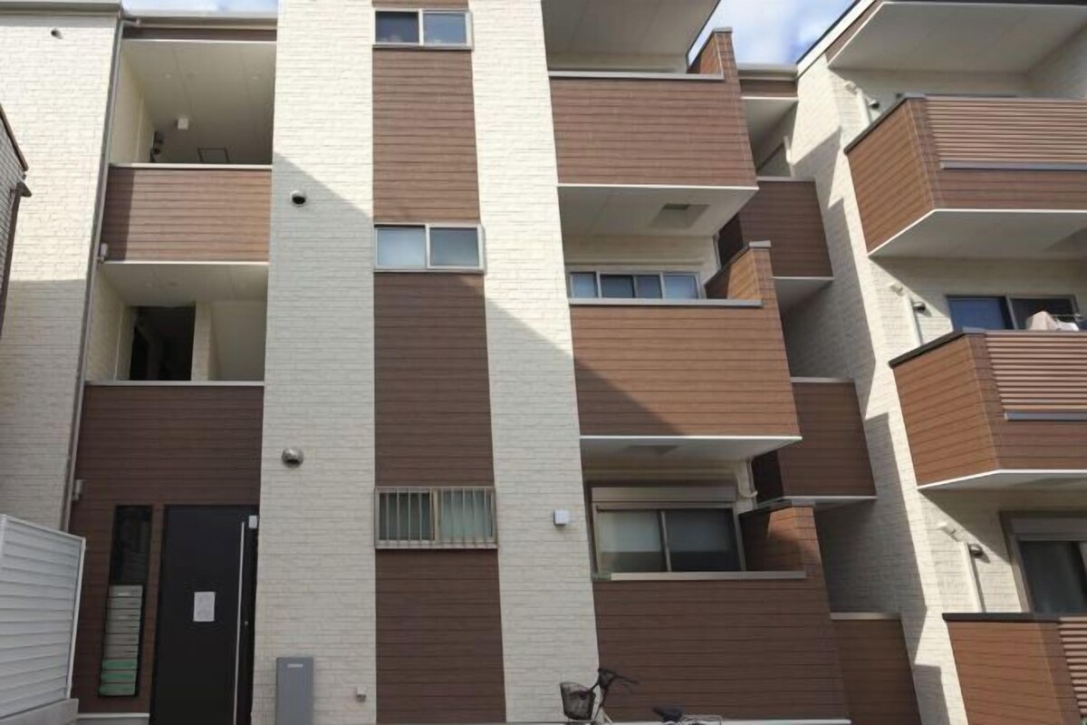 A multi-story residential building with balconies, a door, and a window.