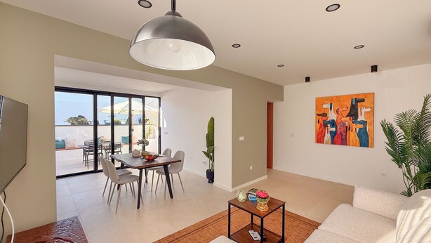 Un salon moderne comprenant un canapé, une table basse et un coin repas avec des chaises et une table.