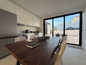 A modern kitchen with a dining area, large sliding glass doors, and a view of the outside.