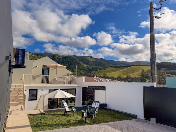 A modern outdoor patio with a view of green hills and a clear sky.