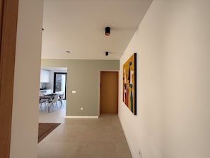 A hallway with a dining area, a wooden door, and a wall-mounted artwork.