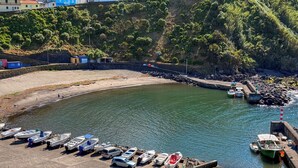 Un port de plaisance avec des bateaux amarrés, une plage de sable et une côte rocheuse.
