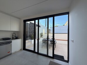 A modern kitchen with a built-in dishwasher, a dining area with a table and chairs, and a sliding glass door leading to an outdoor patio.