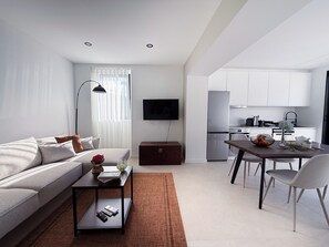 Una sala de estar moderna con un sofá, una mesa de centro y un comedor con una mesa y sillas.