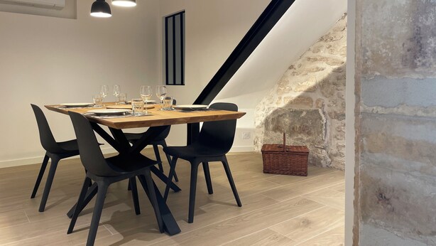 A dining area with a wooden table set for four, black chairs, and pendant lighting.